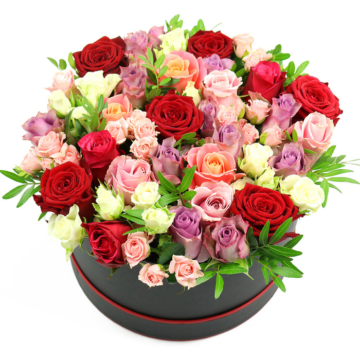 In this image, a sumptuous round bouquet of roses overflows from a sophisticated black cylindrical hat box, accented by a fine, elegant line of red trim at its base, all set against a bright white backdrop. The stark background allows the intricate symphony of colours to take centre stage. The arrangement forms a generous, rounded dome that extends well beyond the rim of the box, creating an impression of abundance and indulgence, like a floral sculpture you might encounter in an elegant Oxford boutique. Deep crimson and scarlet roses are the most striking at first glance, their velvety petals rich with drama and passion. Around them, a tapestry of softer tones unfolds: tender blush pink roses, vivid fuchsia blooms, warm coral and apricot shades, and romantic lavender and muted purple roses that offer a quietly sophisticated note. Interspersed throughout are creamy white and ivory flowers, which highlight the depth of the darker hues and give the entire design a luminous quality. The roses vary in maturity, with some fully open and layered, others in mid-bloom, and clusters of smaller spray roses adding fine detail and a more natural, garden-like feel. Subtle strands of fresh green foliage, perhaps ruscus or eucalyptus, peek out here and there, breaking up the colour and lending a fresh, just-arranged character. The composition feels meticulously planned yet effortlessly lush, the kind of premium hat box design that would be carefully prepared at Flowers Oxford for same-day delivery across the city, from Summertown to Cowley. Ideal for anniversaries, Valentine's Day, significant birthdays, or heartfelt congratulations, the arrangement communicates romance, admiration, and generous appreciation in one lavish gift.
