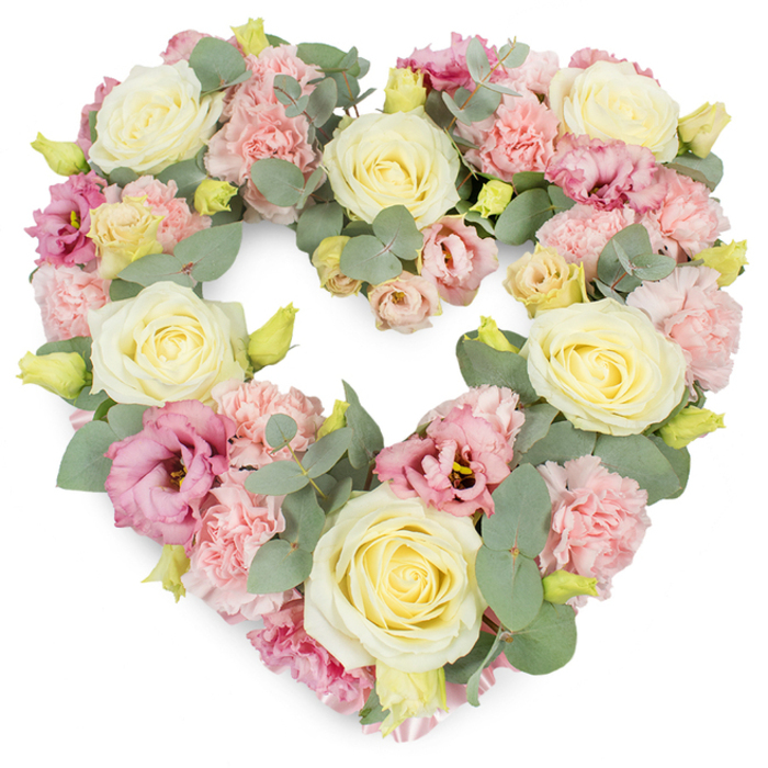 A beautifully crafted heart-shaped wreath fills the image, its abundant flowers and foliage radiating a sense of calm, dignified love that would feel at home in any Oxford chapel or churchyard. The heart's outline is clearly defined, yet softened by generous clusters of silvery-green eucalyptus, their smooth, rounded leaves overlapping to create a gentle, mist-like halo around the blooms. Within this leafy frame, creamy ivory and pale yellow roses are carefully spaced as structural anchors, each rose a perfectly formed rosette with petals that curl inwards at the centre, then unfold in soft, layered spirals. Their subtle fragrance can almost be imagined-clean, comforting, and familiar. Between them, pastel pink carnations fill the spaces with their intricate, frilled petals, building a plush, cushiony texture that makes the heart look irresistibly soft to the touch. Deeper tones come from mauve and magenta lisianthus, whose slightly ruffled, bell-shaped blooms introduce a tender contrast, reminiscent of the dusky shades that fall over Oxford's historic spires at evening. Delicate yellow-green buds are tucked here and there among the flowers, like small sparks of new life, suggesting hope amid grief. The entire composition is densely packed, leaving no harsh edges, and the pristine white background helps every colour and texture stand out clearly. This heart wreath feels deeply personal, ideal as a tribute at a funeral, memorial, or celebration of life for someone who loved Oxford-perhaps a quiet farewell in Wolvercote Cemetery or a service near the colleges. It speaks of remembrance, loyalty, and enduring affection, a final gesture that holds memories close in a gentle floral embrace.