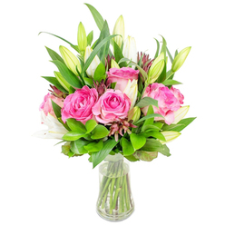 Imagine a fresh, vibrant grouping of fully opened deep pink roses paired with poised white lily buds, arranged with the measured eye of a local florist and presented in a clear glass vase that reveals neatly trimmed stems in bright, clean water. The roses form a warm, central cluster - their petals soft and velvety, moving from deep fuchsia at the heart to gentler blush tones at the edges - while the lilies, some still tightly furled and others just beginning to show trumpet-shaped blooms, introduce an elegant vertical rhythm and a quiet, powdery scent. Surrounding foliage provides a generous, verdant frame: broad glossy leaves, slimmer mid-green stems, and delicate sprigs that soften edges and increase the bouquet's fullness. Small, deeper burgundy or reddish-brown accents are woven through the greens, adding subtle shadow and textural contrast to the otherwise bright palette. The slightly tapered vase and clear water give the whole composition a light, airy feel appropriate for a bedside table, office desk, or centrepiece for a celebratory meal in Summertown or by the riverside near Magdalen Bridge. As one of the florists at Flowers Oxford, I arrange these stems to communicate warmth and thoughtful intention, and we often offer local delivery across Jericho and Headington for last-minute gifts. The finished bouquet reads as refined yet generous, perfect for birthdays, anniversaries, or simply to send a hopeful, fragrant hello to someone you love in and around Oxford.