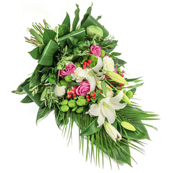 Evoking the tranquil beauty of Oxford's riverside parks, this cascading floral spray weaves together shades of white, pink, green, and red in a dignified tribute for a meaningful farewell. The eye is naturally drawn along the flowing diagonal line, from top left to bottom right, where lilies with wide, star-shaped blooms and visible golden stamens rest alongside those still in bud, imbued with a subtle, soothing perfume. Rich fuchsia roses, their petals gently opening, nestle amid the lilies, suggesting warmth and heartfelt remembrance akin to the traditions carried through the city's collegiate halls. Small white spray carnations and mossy green santini chrysanthemums add texture and dimension, echoing the softness and vibrancy of spring mornings in South Park. Glossy, deep green foliage-some leaves elegantly folded, others light and feathery-creates a sculpted foundation, while trailing palm fronds flow like gentle river currents beneath Magdalen College Bridge. Bright red hypericum berries, artfully interspersed, provide unexpected pops of cheer against the calming palette. This arrangement, suitable as a sympathy tribute or funeral spray, balances architectural precision with natural grace, offering comfort and condolence throughout Oxford-from Jericho's historic streets to the modern heart of Headington. Such a bouquet speaks where words may falter, reflecting both skilled craftsmanship and local compassion.