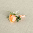 Framed in gentle daylight on a textured taupe cloth, this buttonhole feels like a small, private promise. The focal point is a single apricot-tinged rose whose tightly rolled center unfurls into soft, satiny petals that graduate from warm orange to a whisper of cream; the surface of each petal looks almost translucent where the light grazes it. Sprigs of white gypsophila nestle alongside the rose, their clustered pinhead blooms lending an ethereal, confetti-like lightness that lifts the composition. Curved, glossy green leaves are folded into themselves in elegant loops, offering subtle contrast and a contemporary silhouette against the classic rose shape, while narrow bright-green grass blades thread through to add a lively, organic texture. The stems are wrapped with a matching peach satin ribbon, finished with a tidy knot and a small metallic pin tucked close to the base - practical but discreet, a finishing touch that speaks of preparedness for a lapel or corsage. The backdrop's woven weave suggests a natural linen surface, neutral enough to let the flower's warm tones take centre stage. This is the sort of boutonniere I'd place beside a table setting at an intimate Oxford reception near the Covered Market or slip into the pocket of a suit for a summer dance at University Parks; it conveys restraint, sincerity, and a light fragrant hint of rose that promises comfort rather than flourish. Expertly balanced and unassuming, it honours moments of joy with a soft, enduring grace.