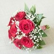 Arranged with a professional florist's care and resting upon a neutral, cream-toned linen reminiscent of an Oxford dining hall table, this timeless bouquet blends the passionate allure of five or six sumptuous, velvet-petaled red roses with the soft, cloudlike delicacy of white baby's breath (Gypsophila). Each rose, adorned in lush crimson, opens gracefully, surrounded by airy clusters of tiny white blossoms that lend a gentle lightness to the overall form. Vibrant green leaves-possibly sprigs of ruscus or eucalyptus-hide tenderly among the blooms, their dewy surfaces capturing hints of the city's verdant spring mornings. The stems are thoughtfully gathered and wrapped with a refined red and white striped ribbon, finished with a twirling string of shining white pearls-a nod to both modern elegance and the classic Oxford spirit. Balanced lighting enhances the bouquet's rich textural details and lively colours, spotlighting the craftsmanship behind each floral choice. Perfect for an Oxford wedding along the Cherwell or as a romantic gesture on Broad Street, this bouquet radiates heartfelt celebration, love, and enduring sentiment, reflecting the artistry and passion of its local makers.