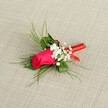 A single elegant boutonnière lies diagonally across a softly textured, light beige fabric, the neutral background reminiscent of natural linen and the calm stone facades around Oxford's historic colleges. At its heart sits a tightly furled fuchsia rosebud, edging towards deep magenta, its petals smooth and velvety, cupped closely together in a perfect spiral that feels poised to unfurl. Clusters of tiny, cloud-like white baby's breath nestle around the rose, each miniature blossom adding a soft halo of lightness that gently breaks up the intensity of the pink. Behind and around the flowers, fine, feathery fronds of bright green foliage, similar to asparagus fern or delicately cut ruscus, fan outward in graceful arcs, their airy texture giving the arrangement height and movement without overpowering the central bloom. The darker, more solid greenery at the base anchors the composition, offering a quiet depth of colour like the shady gardens off St Giles' in early summer. All the stems are carefully gathered and bound with a slim, glossy red satin ribbon, wrapped smoothly and firmly around the base so that no stray ends show, the sheen catching the light as though it has just been finished by an attentive florist. The ribbon's rich red tone echoes the warmth of the rose while adding a polished, formal touch, perfect for fastening to a lapel. Bright, even lighting reveals every detail-the fine veins in the leaves, the delicate edges of the petals-creating an impression of freshness and care, ideal for a groom or prom guest in Oxford seeking a refined, romantic accent to complement a suit or tuxedo on a special day.