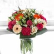 As I take in this vibrant Oxford bouquet, it feels like a celebration in full bloom-a spirited composition of orange gerberas, blushing pink roses, and rich, velvety magenta carnations. Creamy ivory roses and soft, peach-hued gerberas provide gentle balance, bringing an air of elegance and affection to the overall design. Deep, glossy greens frame and support the flowers, their crispness evoking the abundant foliage of Oxford's college gardens. Brilliant, natural light illuminates the scene, catching the delicate veins of each petal and causing the array of colours to shimmer-a scene reminiscent of a sunlit walk through Radcliffe Square. This arrangement is perfect for commemorating milestones, marking birthdays in Jericho, or simply spreading cheer to loved ones across Oxford. It's a moment of happiness preserved, crafted with an expert's attention to harmony and the nuances of seasonal beauty, inviting the recipient to feel both celebration and the warmth of local floral artistry.
