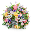 A lush, round bouquet sits against a pure white background, its dome of blossoms casting a soft, natural shadow that underlines the arrangement's volume and careful construction. Close inspection reveals an abundance of garden roses in soft blush pink, buttery yellow and creamy peach, their layered petals unfurling in tight spirals and wider cups to create the romantic core of the design. Star-shaped clematis in pale lavender and near-white pop up between the roses, their open petals and light yellow centers lending a breezy, garden-wild note. Architectural contrast comes from several blue Eryngium (sea holly) thistles - spiky, metallic-blue-grey heads that catch the light like tiny sculptures. Deeper purple lisianthus, from ruffled buds to gently opened cups, nestle into the composition and add soft, velvet tones, while clusters of glossy red Hypericum berries punctuate the massed blooms with cheerful, jewel-like accents. A variety of foliage - broad, glossy leaves for structure, fine, feathery greens for softness, and hints of almost-burgundy filler foliage - fills the spaces and gives the bouquet a layered, tactile depth. The lighting is soft and even, highlighting the textural differences between velvety rose petals, spiky sea holly and shiny berries, and suggesting a fresh, slightly sweet floral fragrance like a summer garden after rain. Thoughtfully balanced for celebrations, centrepieces or a sincere gift, this arrangement would feel at home being delivered across central Oxford - from the Covered Market to University Parks - where its classic palette and handcrafted feel reflect local floral sensibilities.