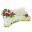 A rectangular pillow-shaped funeral tribute, photographed against a stark white background that throws a soft shadow beneath it, is densely layered with hundreds of small, pristine white chrysanthemum florets to create a cloudlike, plush surface. The chrysanthemums' tightly packed petals form a velvety texture you can almost feel under the fingertips, offering a visual impression of quiet rest and purity. Along the upper-left corner a concentrated spray of deep magenta roses-rich, velvety blooms in full, generous unfurling-sits nestled among delicate white freesia and creamy lisianthus, their slender stems and tiny trumpet flowers adding lightness and a subtle sweet perfume. Sprays of feathery fern fronds and fresh emerald foliage cradle the cluster, giving it depth and a soft, natural frame. From that focal group, two slender, arching stems of bright green linear foliage-likely bear grass-sweep across the cushion in elegant curves, guiding the eye toward the opposite edge where a single magenta rose is placed as a thoughtful counterpoint. The whole pillow is finished with a folded lime-green satin ribbon trim around the perimeter, forming a neat scalloped ruffle that introduces a gentle, hopeful flash of colour and frames the white chrysanthemum field with care. The lighting is even and calm, the composition balanced and reverent, evoking the comfort of peaceful slumber and solemn remembrance. This arrangement reads as a classic sympathy gesture meant to cradle memory and convey solace, the sort of tribute a family might choose when honouring a loved one at a chapel near Christ Church Meadow or a quiet funeral service in Oxford.